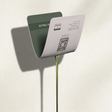 A green and white card labeled 30 PACK (LEGACY) from My Store is attached to a thin metal stand, casting a shadow on a light wall. The travel-ready card displays a QR code and text in English and another language.